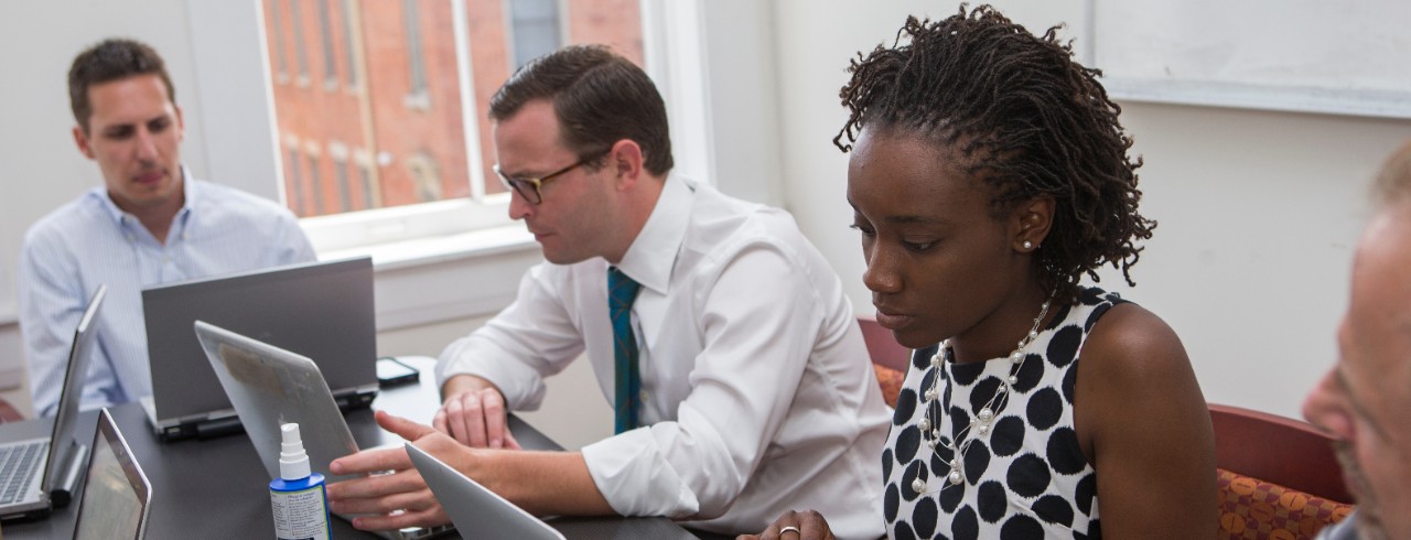 Law students take notes on a laptop while meeting with clients.