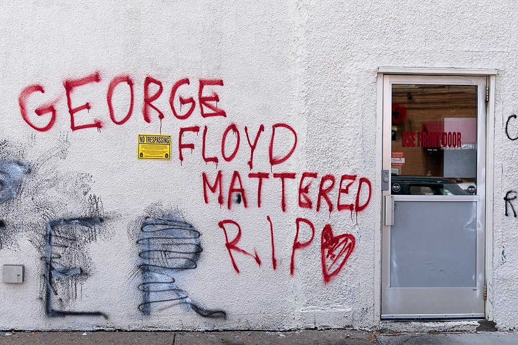 Graffiti on a white wall reading "George Floyd Mattered RIP"