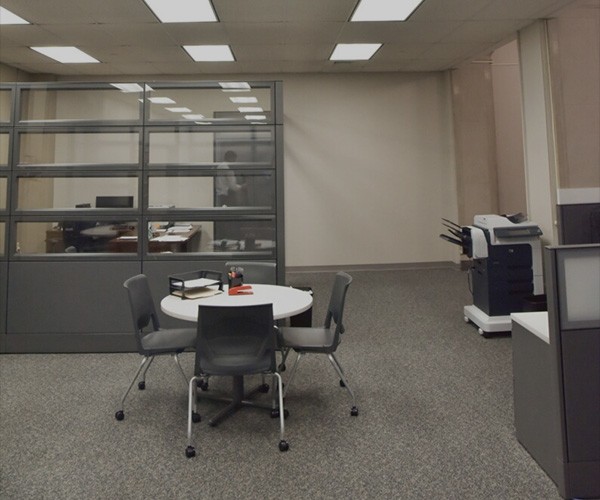 Help Center Office An office space with a round table, 4 chairs and a desk behind a glass screen